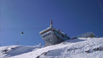 A snow-covered mountain with a ski lift and a building with a sloped roof.