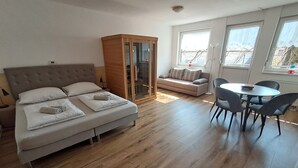 A modern bedroom with a bed, a wardrobe, a sofa, and a dining area. - Apartment Honey Bee with Sauna (Kobarid)