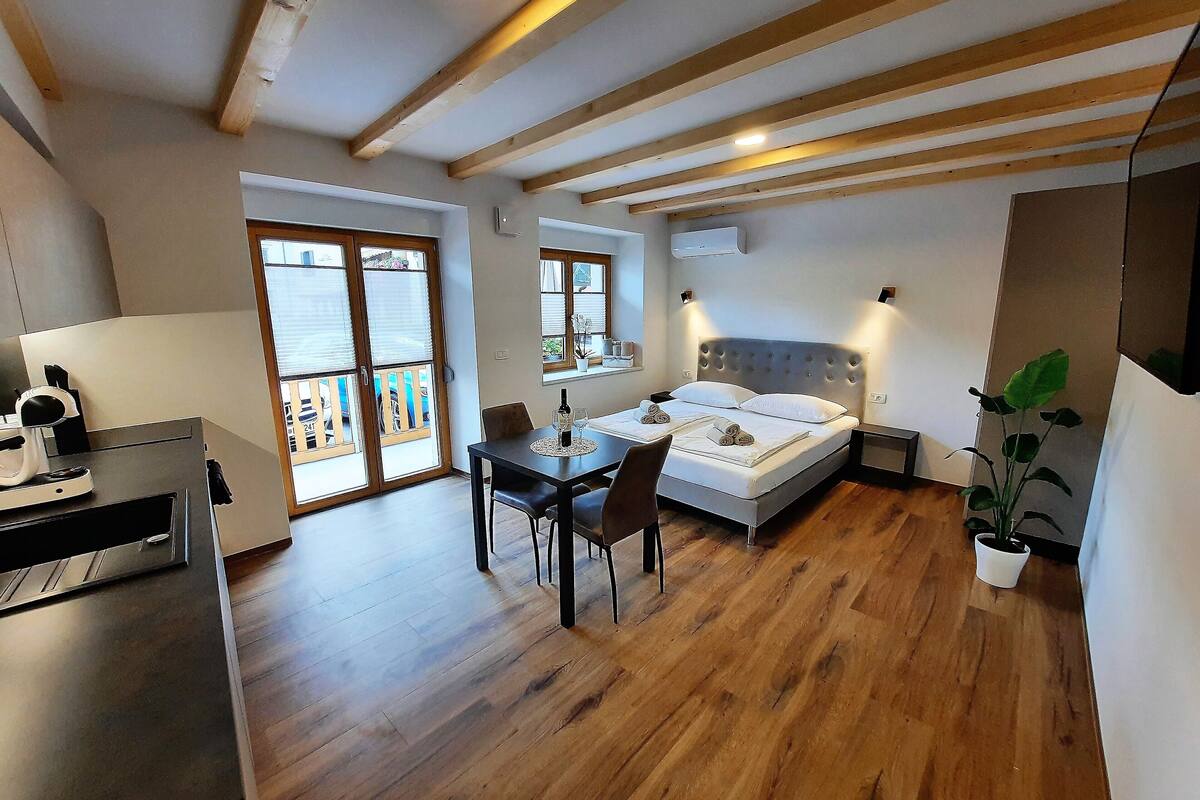 A modern bedroom with a bed, bedside tables, a desk, and a dining area.