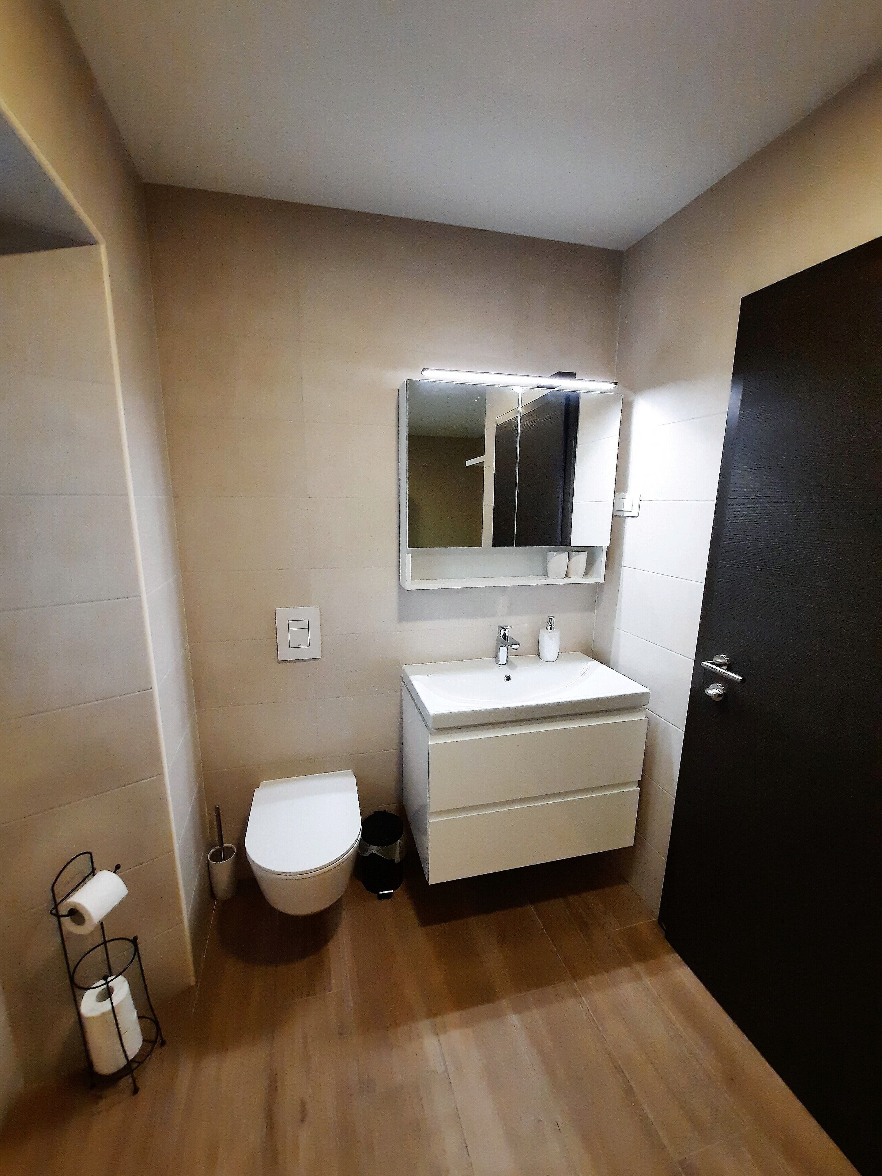 A small bathroom with a toilet, a sink, and a mirror.