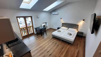 Un dormitorio moderno con tragaluz, una cama con almohadas, una mesita de noche y un pequeño escritorio con una silla.