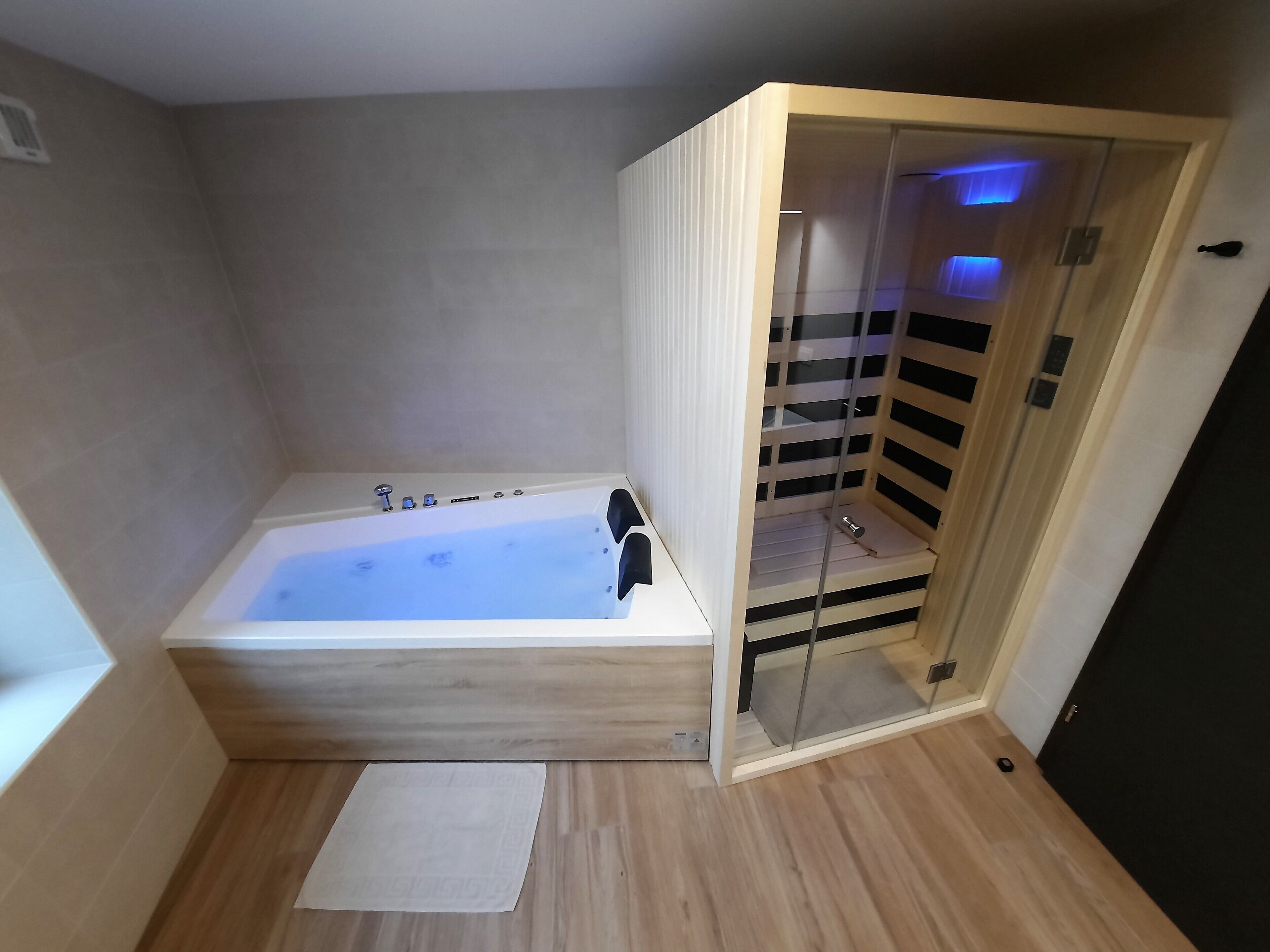 A modern bathroom with a wooden bathtub, a glass-enclosed shower, and a wooden floor.