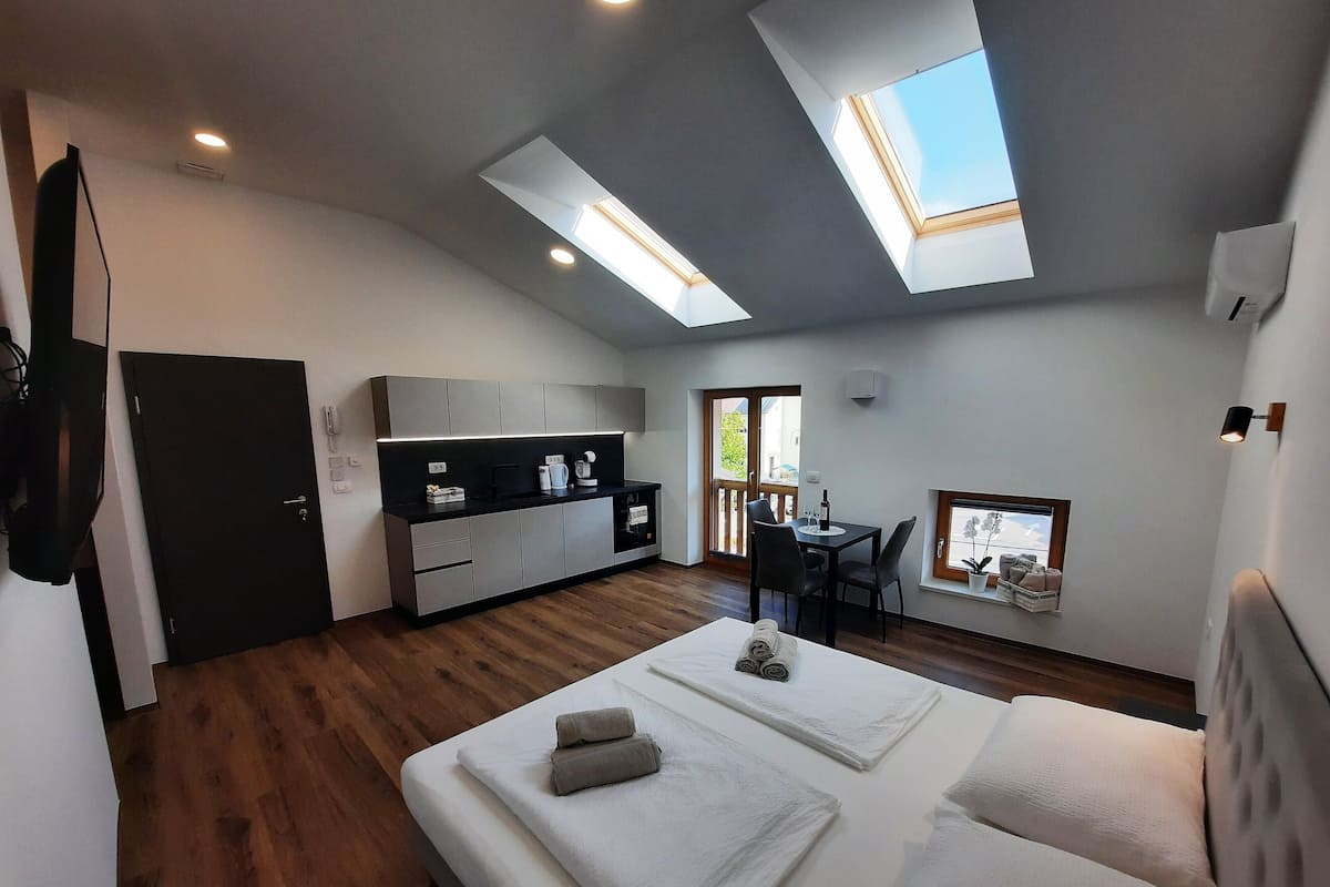 A modern, compact living space with a kitchenette, a dining area, and a bedroom with a skylight.