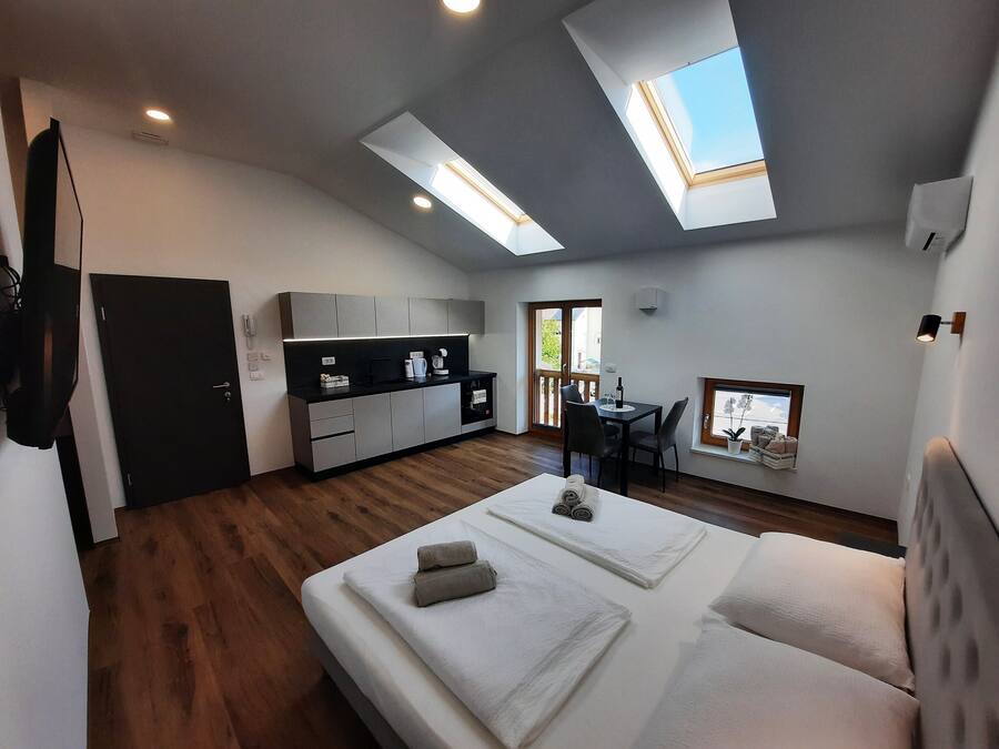 Un espace de vie moderne et compact comprenant une kitchenette, un coin repas et une chambre dotée d’une lucarne.