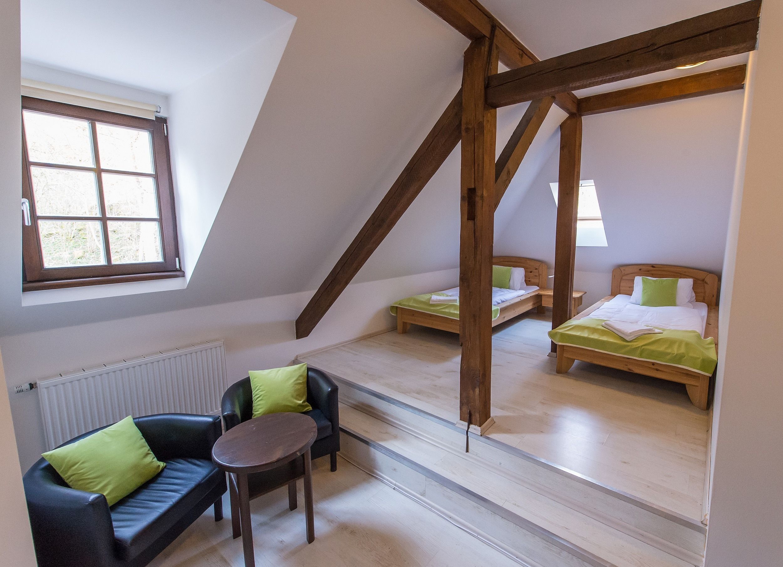 Un dormitorio tipo loft con dos camas de madera, un pequeño sofá y una mesa.