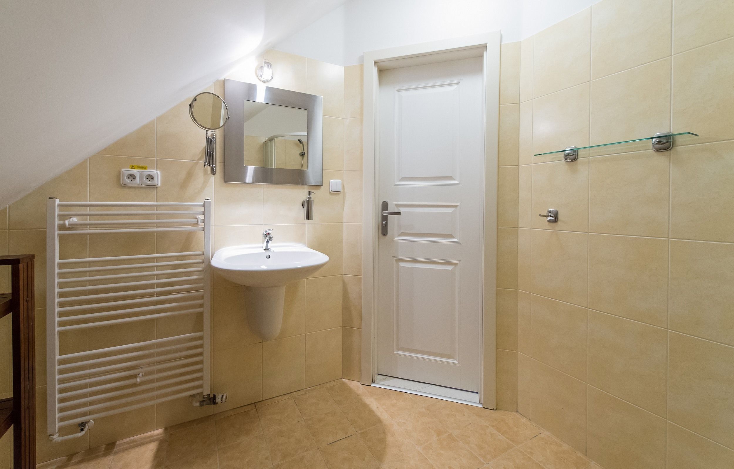 A small bathroom with a white sink, a mirror, a towel rack, and a door.