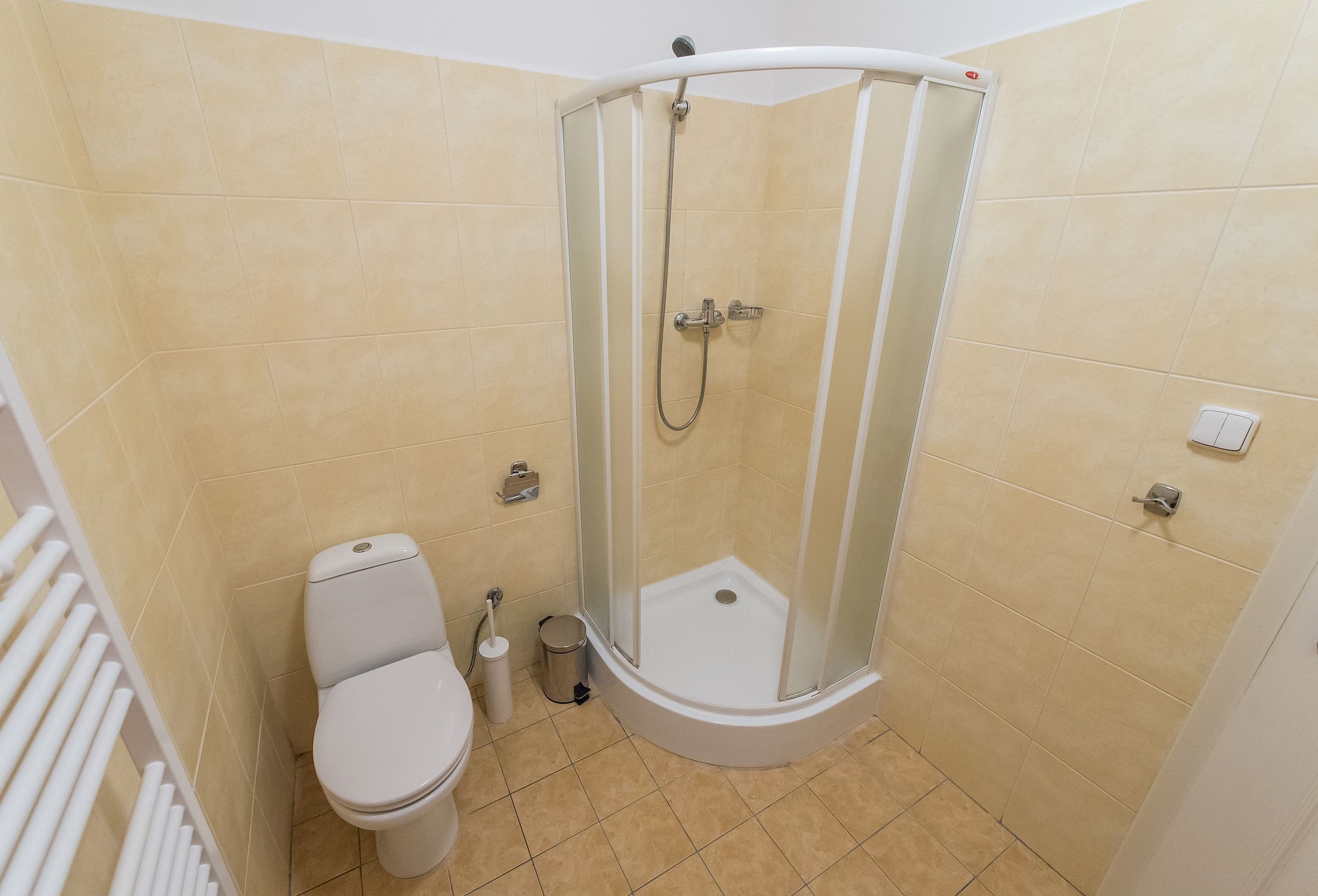 Un baño con inodoro, cabina de ducha y secamanos.