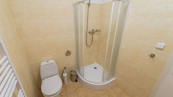 Un baño con inodoro, cabina de ducha y secamanos.