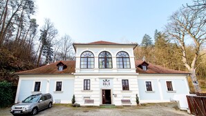 A two-story building with a symmetrical facade, a central entrance with a coat of arms, and a gravel driveway.