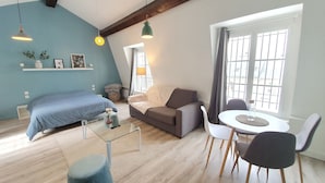 Una sala moderna con cama, sofá, mesa de comedor y sillas.