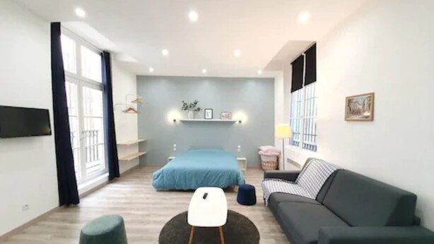 Un dormitorio moderno y bien iluminado, con una cama grande, un sofá y una pequeña mesa redonda.