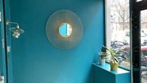Una habitación con paredes color turquesa, un espejo decorativo y una planta en maceta.