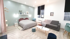 Un dormitorio moderno con cama, sofá, mesa de centro y ventana con persianas.