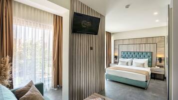 Una habitación de hotel moderna con una cama grande, un televisor montado en la pared y vistas al exterior a través de grandes ventanales.