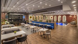 Ein modernes Restaurant mit Barbereich, Sitzgelegenheiten mit Tischen und Stühlen sowie einem Poolbereich.