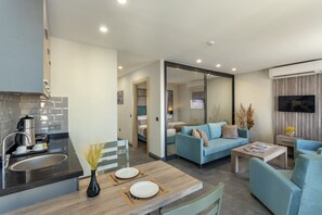 A modern kitchen with a sink, stove, and dining area. There is a living room with a sofa and a coffee table. - Rodinn Park Hotel (Konyaalti)