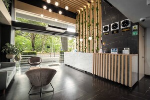 A modern reception area with a marble reception desk, a wooden reception stand, and a seating area with a chair.