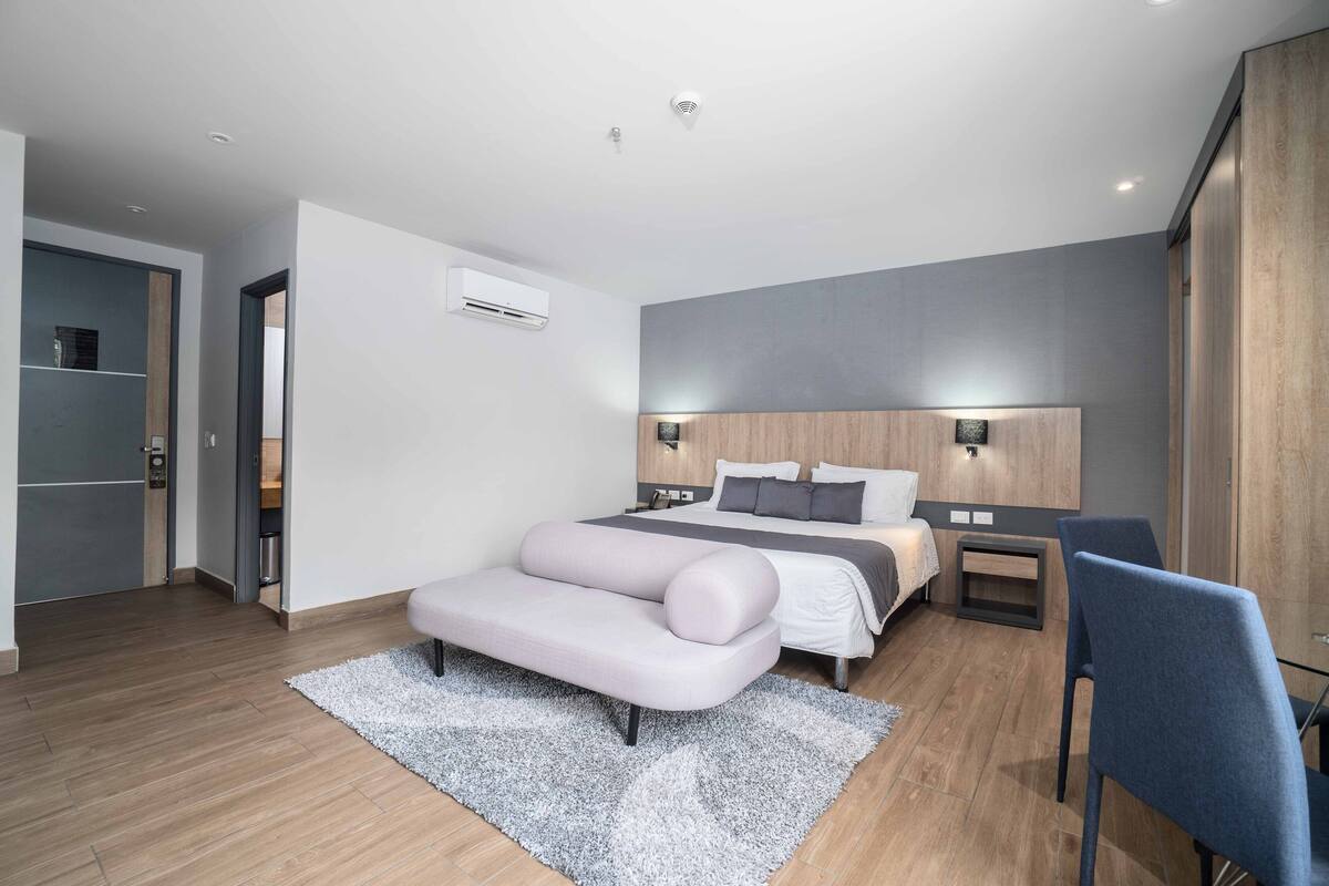 A modern bedroom with a bed, bedside tables, a chair, and a wardrobe.