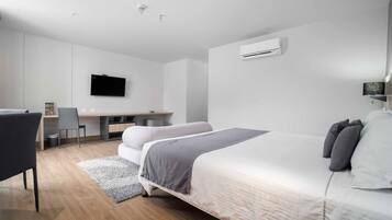 Ett modernt hotellrum med en säng, ett skrivbord, en stol och en TV.