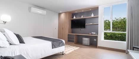 Una camera da letto moderna con un letto, telefono sul comodino, TV integrata e un angolo scrivania.
