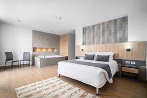 Suite, bañera de hidromasaje | Edredones de plumas, colchones con acolchado adicional, minibar