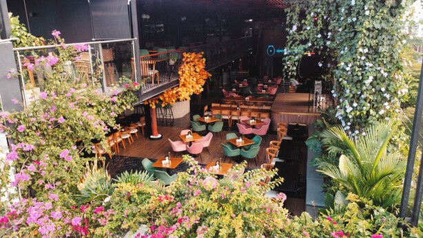 An indoor restaurant with multiple dining areas, including a bar and seating with a view of the surrounding greenery. - Hotel Plaza Del Lili (Cali)