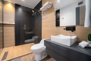 Features a sleek sink, separate toilet, and glass-enclosed shower area.