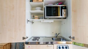 Une cuisine de taille réduite équipée d’un four à micro-ondes, d’un évier et d’une cuisinière.