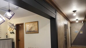 Un pasillo con una recepción, un cuadro enmarcado y una puerta de madera.