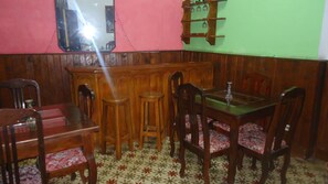 A corner room with wooden paneling, a wooden table with chairs, a mirror, and a wall-mounted shelf with glasses. - Hostal Vista Al Puerto (Havana)