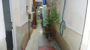 A narrow corridor with a tiled floor, a red drain cover, and potted plants. - Hostal Vista Al Puerto (Havana)