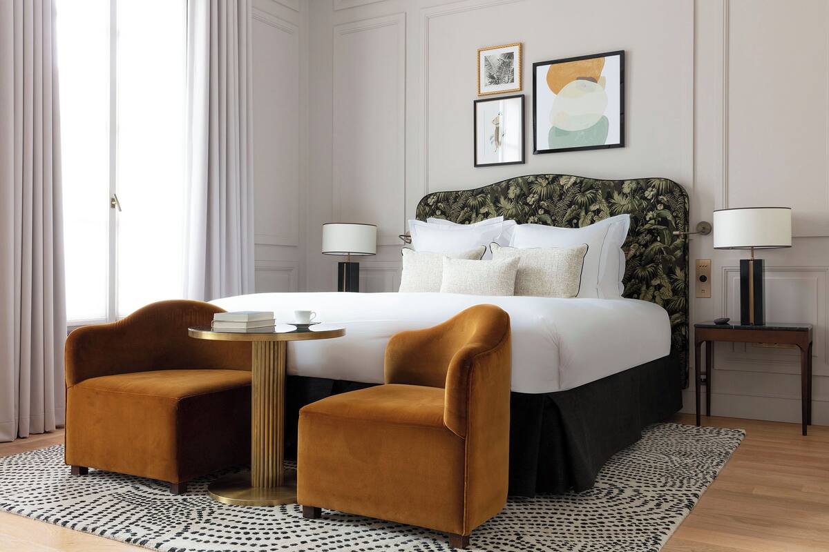 Een hotelkamer met een bed, twee fauteuils, een kleine ronde tafel en twee bedlampjes.