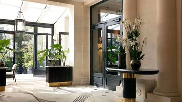 Un vestíbulo amplio con ventanas grandes, una recepción moderna y plantas en macetas.