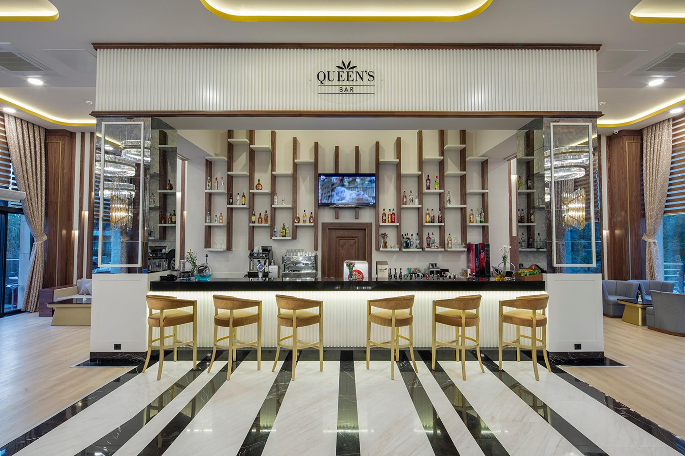 Zona de bar con televisor, estantes con botellas y taburetes de madera.