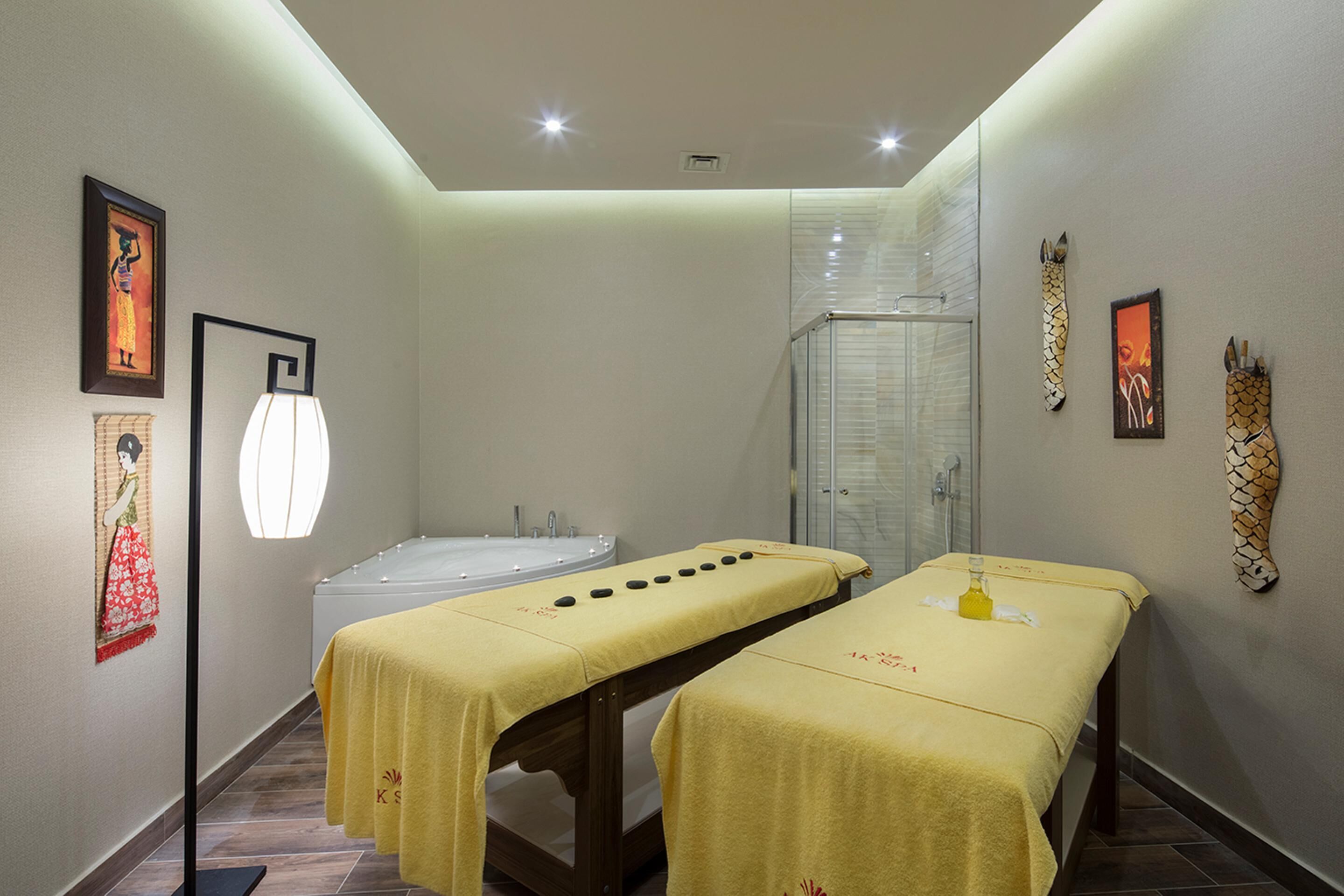 A spa room with two massage tables, a bathtub, and a glass shower enclosure.
