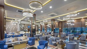Un moderno vestíbulo de hotel con varias zonas de estar, grandes candelabros y un bar.