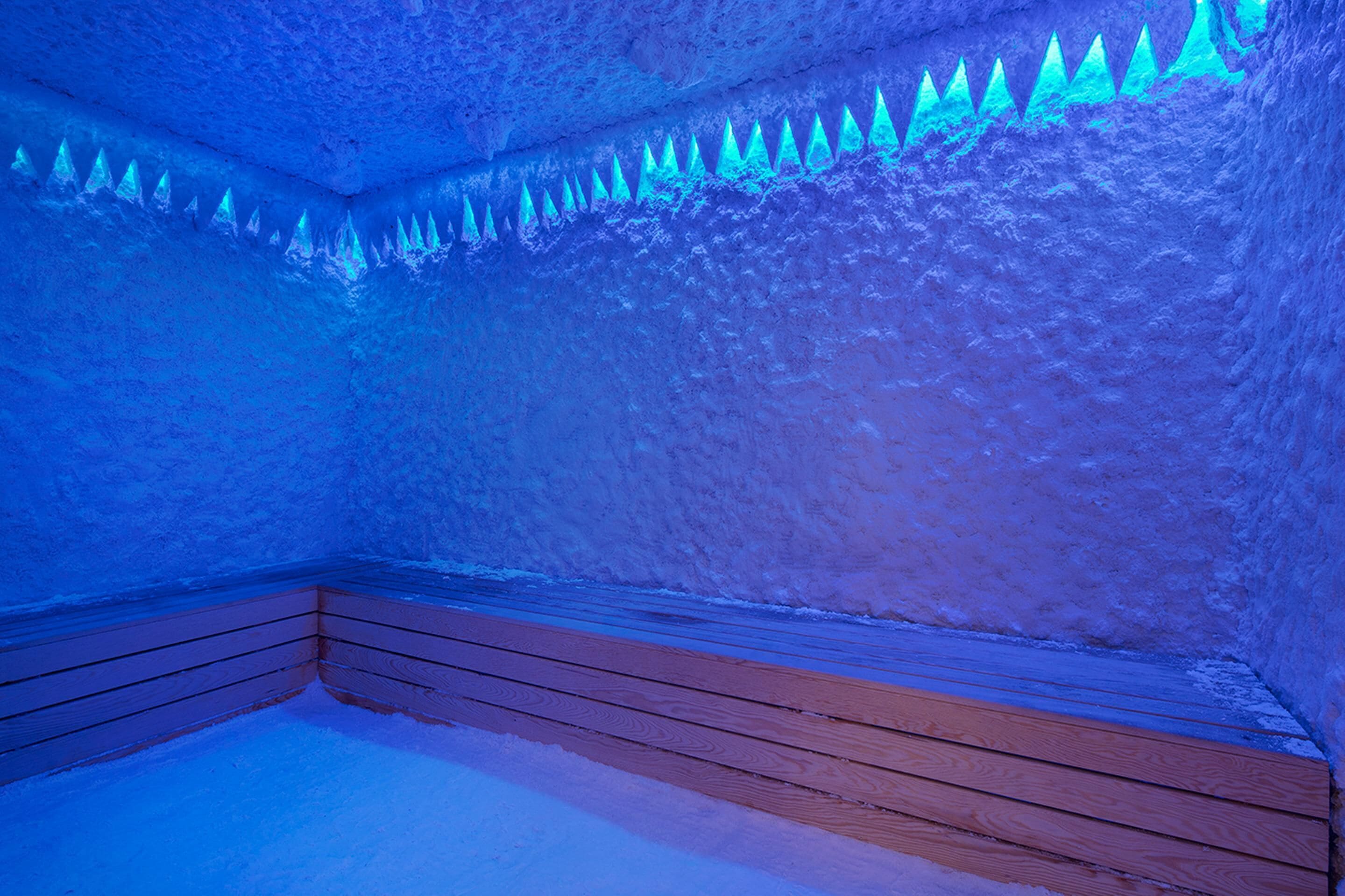 Una cueva de hielo con bancos de madera y formaciones de estalactitas de hielo.