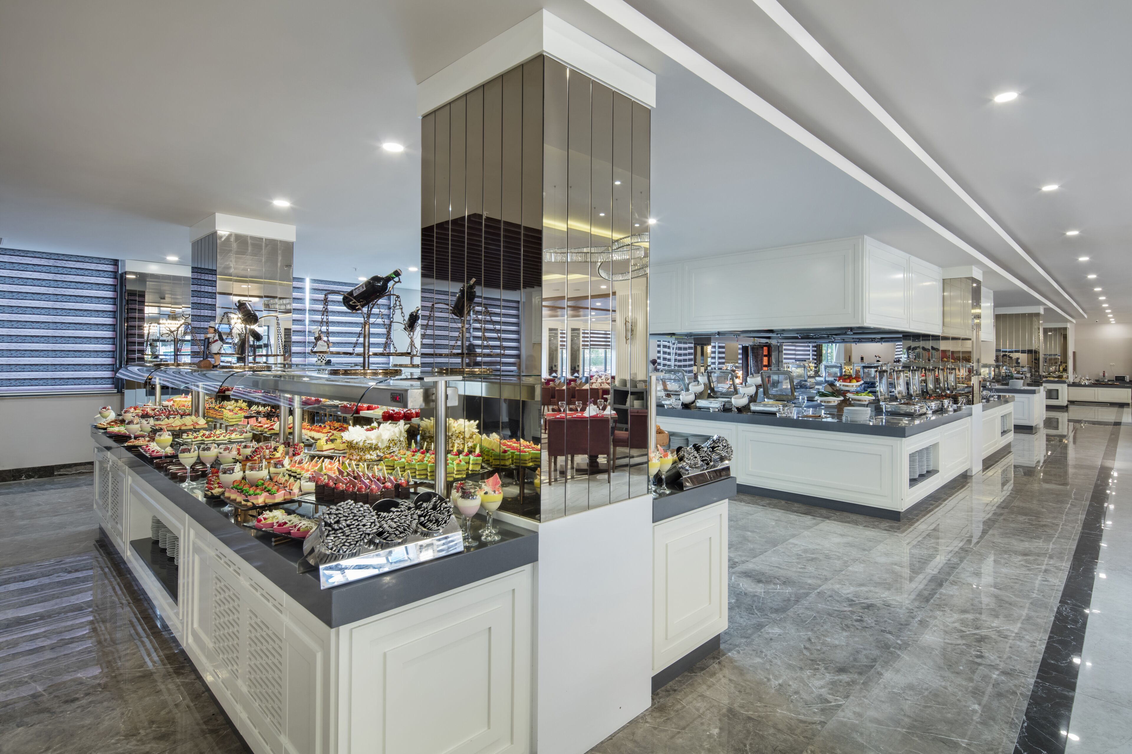 A modern hotel lobby with a buffet area featuring various food items and a seating area.