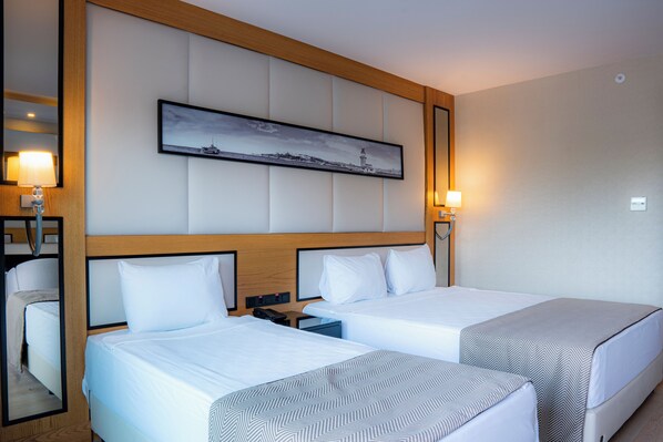 A hotel room with two beds, a nightstand, a lamp, a framed picture on the wall, and a wooden headboard.