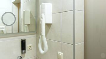 Une salle de bain équipée d’un lavabo, d’un miroir, d’un sèche-cheveux et d’un distributeur de serviettes.