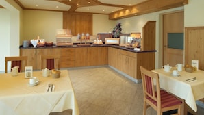 A spacious kitchen with wooden cabinets, a breakfast bar, and a dining area with tables set for breakfast. - Hotel zur Linde (Lohberg)