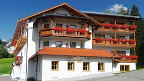 A multi-story building with balconies adorned with red flowers, a sign indicating a restaurant, and a clear sky. - Hotel zur Linde (Lohberg)