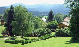 Bairro residencial com casas, um parquinho e montanhas ao fundo.