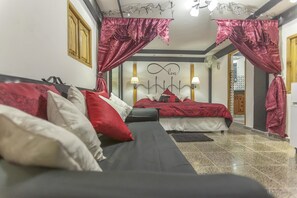 A bedroom with two beds, red and white bedding, a black sofa, and a ceiling fan. - Hostal Zanja (Havana)