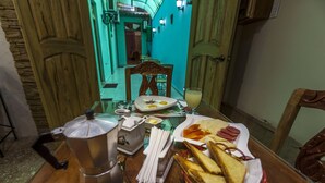 Een eettafel met een koffiepot, een bord eten en een broodmand.