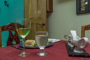 A dining table with two wine glasses, a plate of food, and a napkin holder. - Hostal Zanja (Havana)