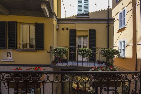 A yellow building with a balcony, potted plants, and a statue. - Appartamento Il Centro (Bellagio)