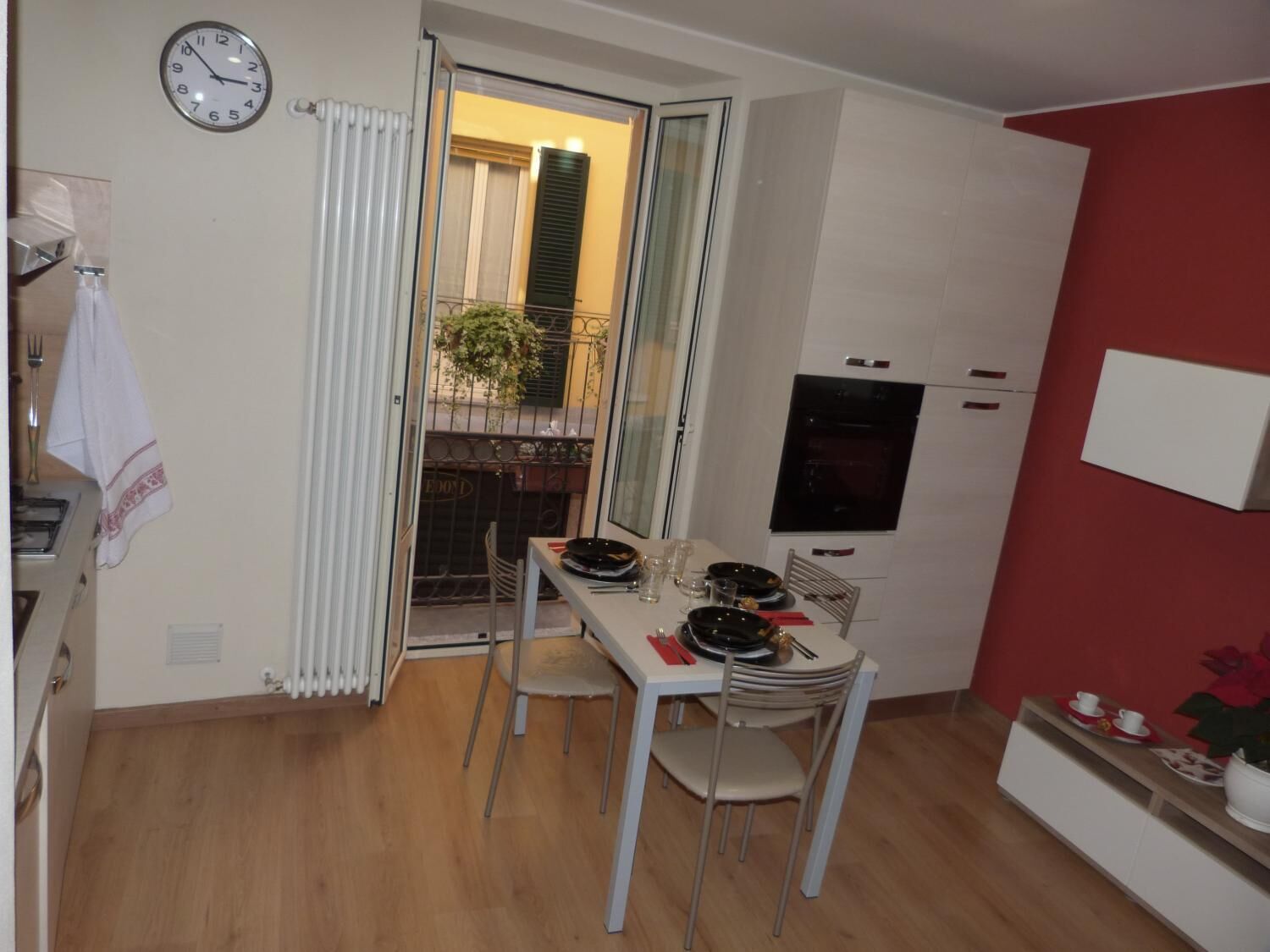 Cocina compacta con mesa, sillas, un reloj y radiador.
