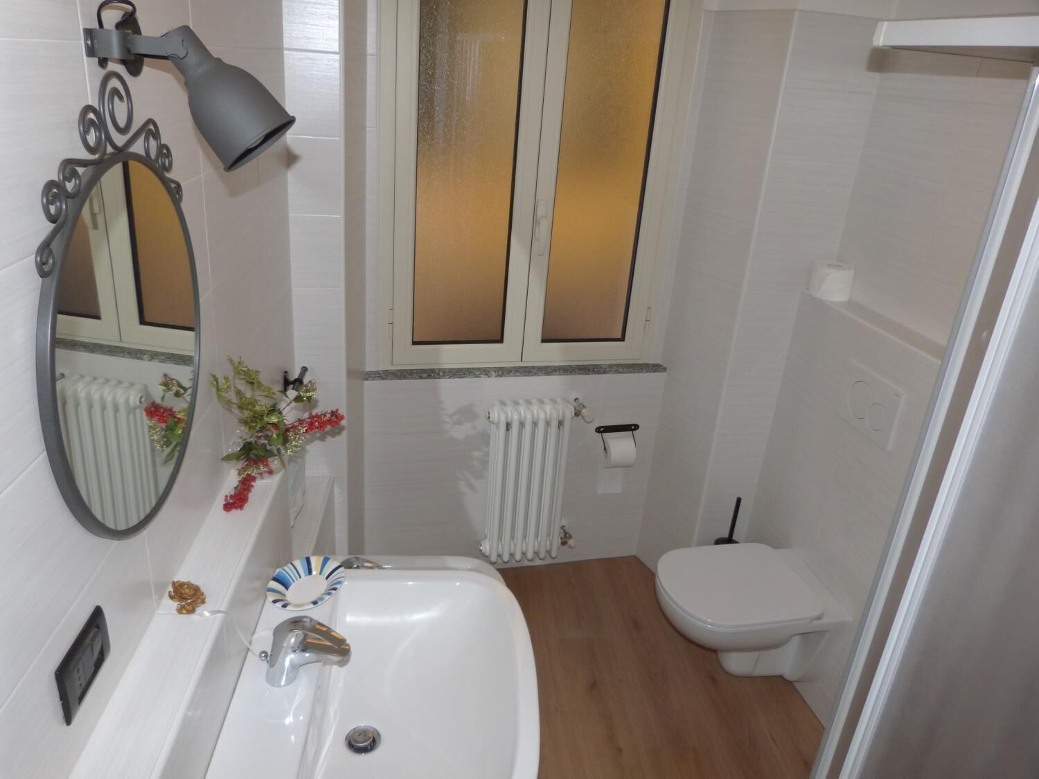 A bathroom with a white sink, a mirror, a toilet, and a shower area.