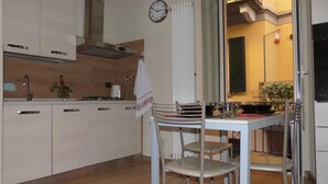 Eine moderne Küche mit weißen Schränken, einer Edelstahl-Dunstabzugshaube und einem Essbereich mit Tisch für zwei Personen.